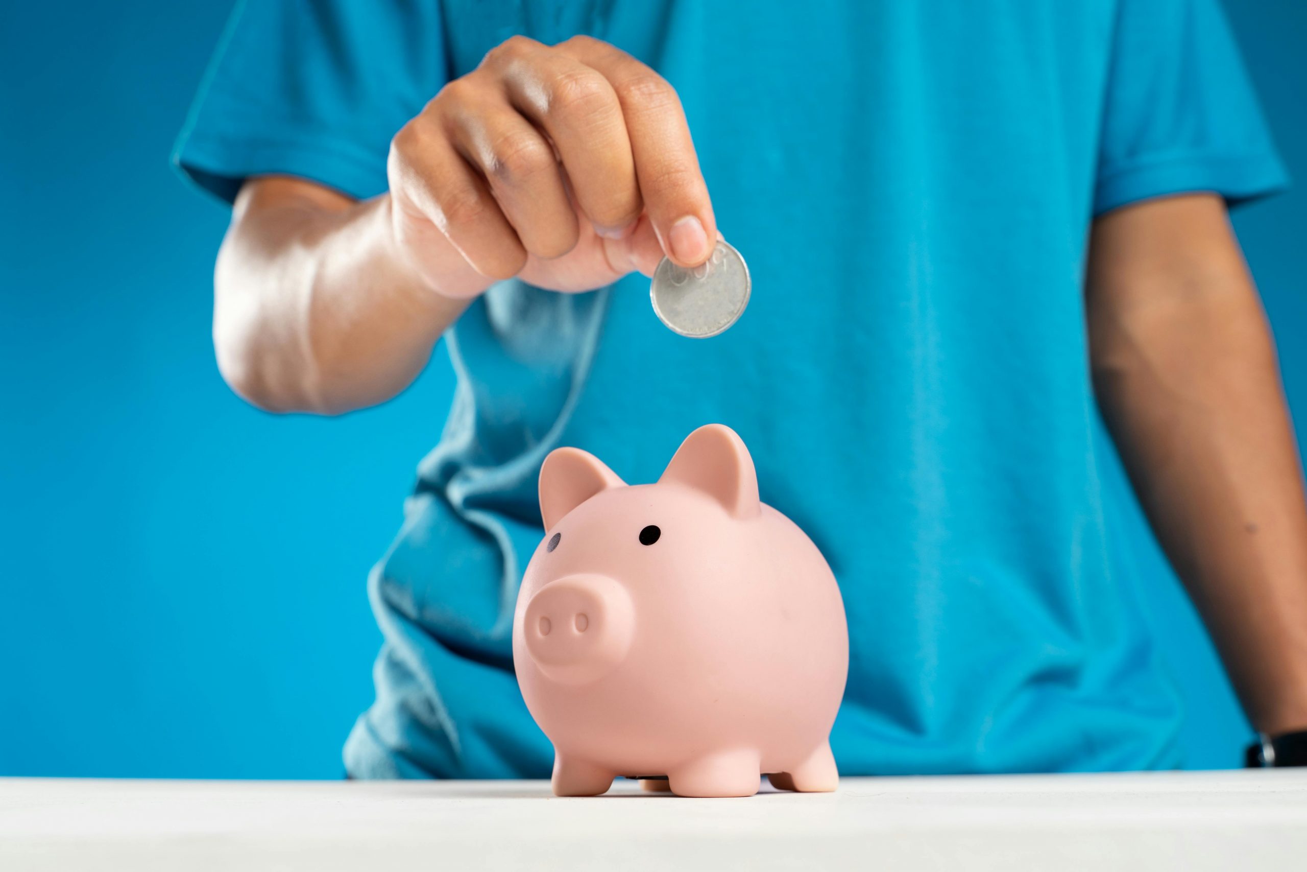 man putting a coin into a piggy bank