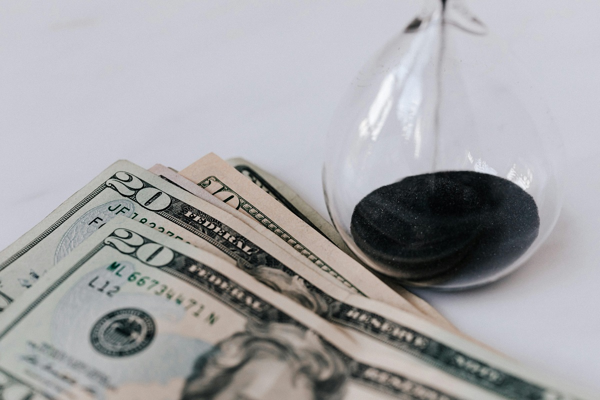 an hourglass and dollar bills