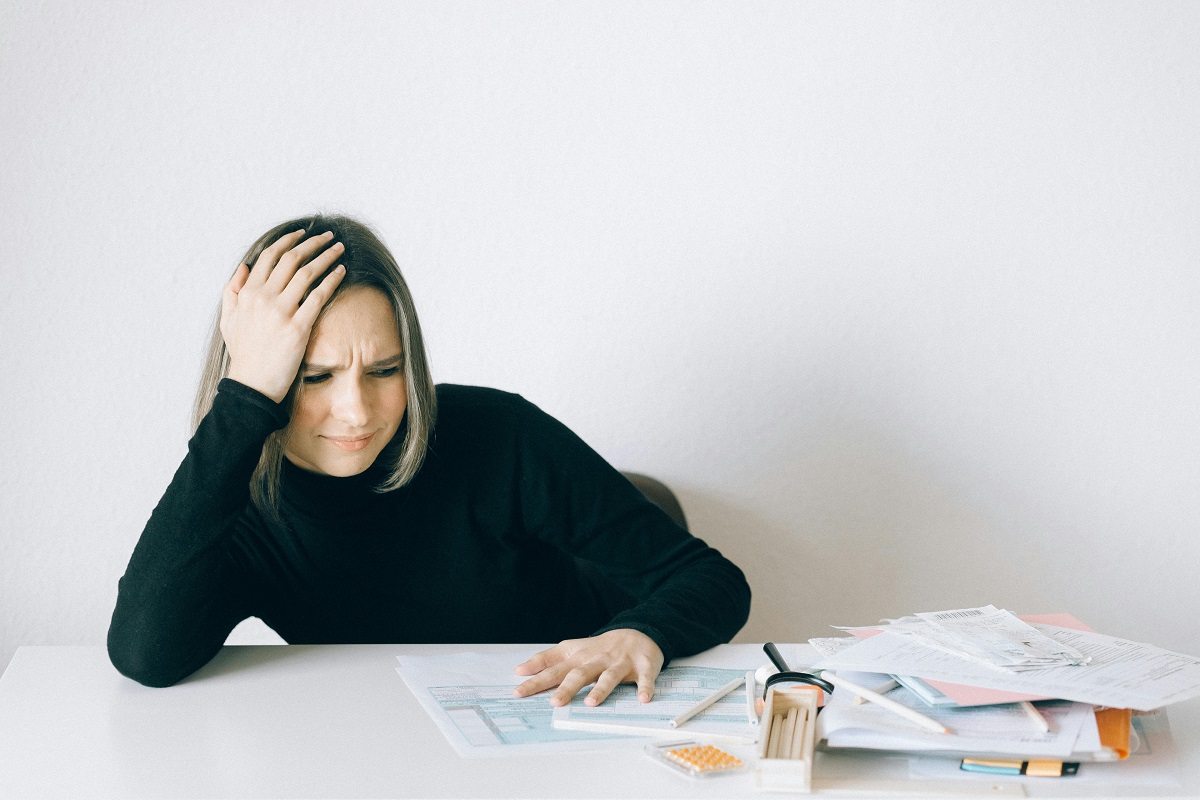 woman resting her head on her hand and frowning at financial documents on the desk