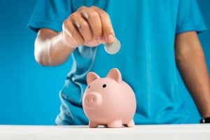 man putting a coin into a piggy bank