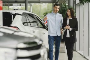woman speaking with a potential customer who is pointing at a car in a dealership