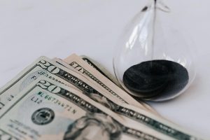an hourglass and dollar bills